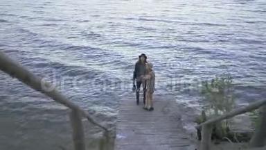 年轻夫妇走在小码头上聊天。 情侣们一起在海滨度过时光